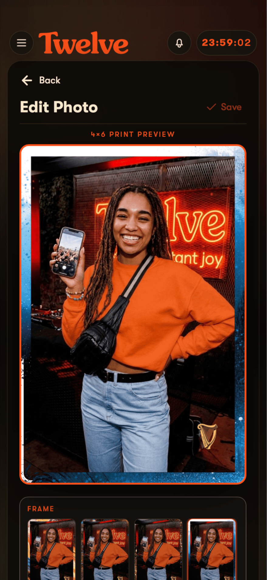 The Edit Photo screen showing a 4x6 print preview: a supporter in an orange sweatshirt holds up her phone in front of a lit Twelve sign, the photograph set inside a branded frame with the Guinness harp in its lower-right corner, and a row of alternative frames to choose from underneath.