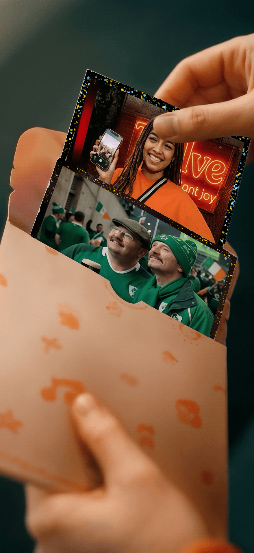 Hands drawing matte prints of the Ireland women's team and their supporters out of a patterned orange Twelve envelope, one print showing a banner reading &ldquo;Ireland women in green&rdquo;.