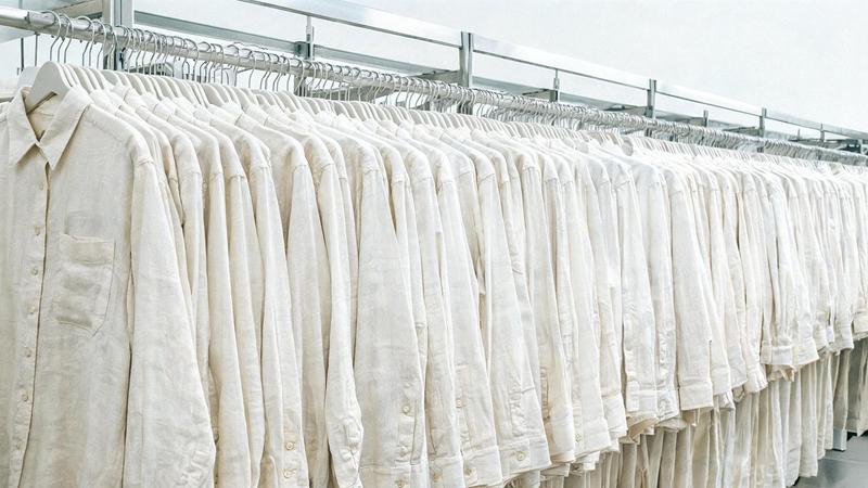 A long rail packed with dozens of near-identical ivory linen shirts