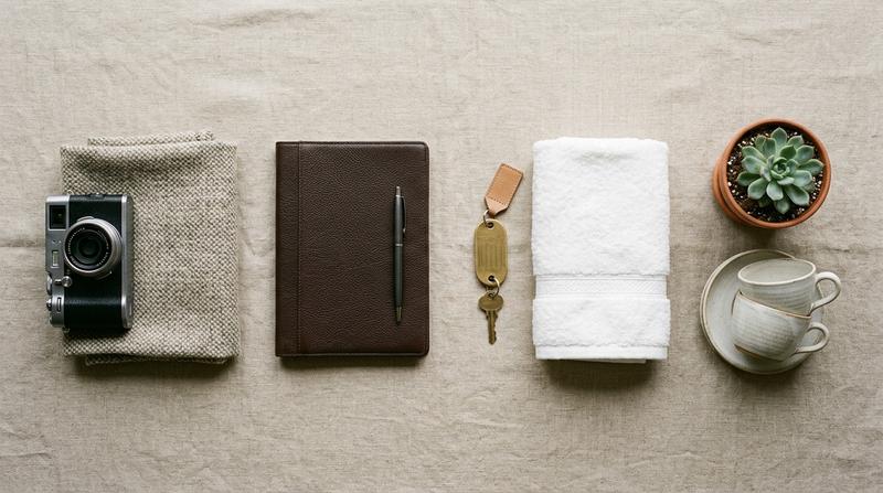 Four groupings of hospitality objects arranged in sequence on a linen surface, shot from above